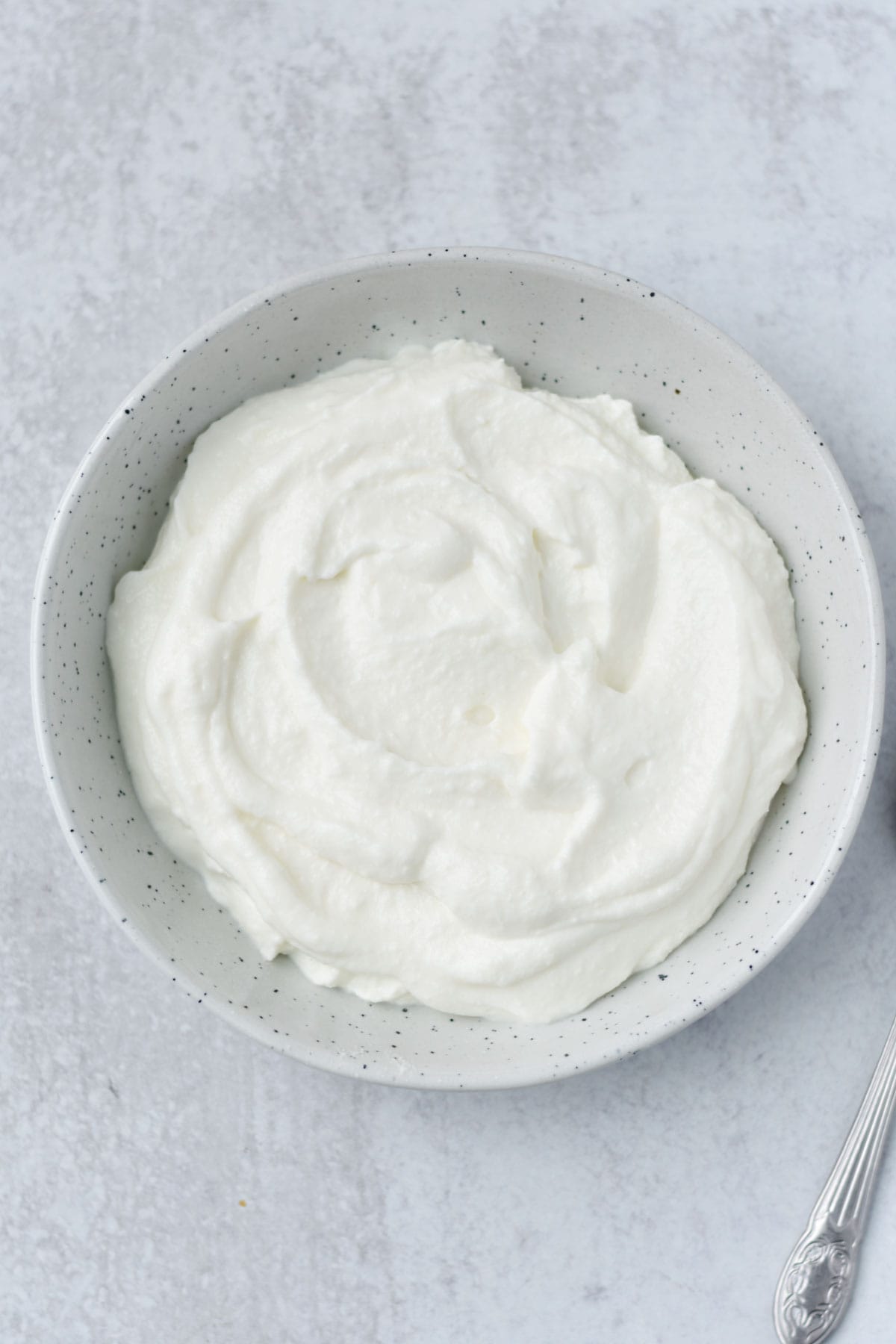 A bowl of smooth, fluffy cottage cheese with a spoon.