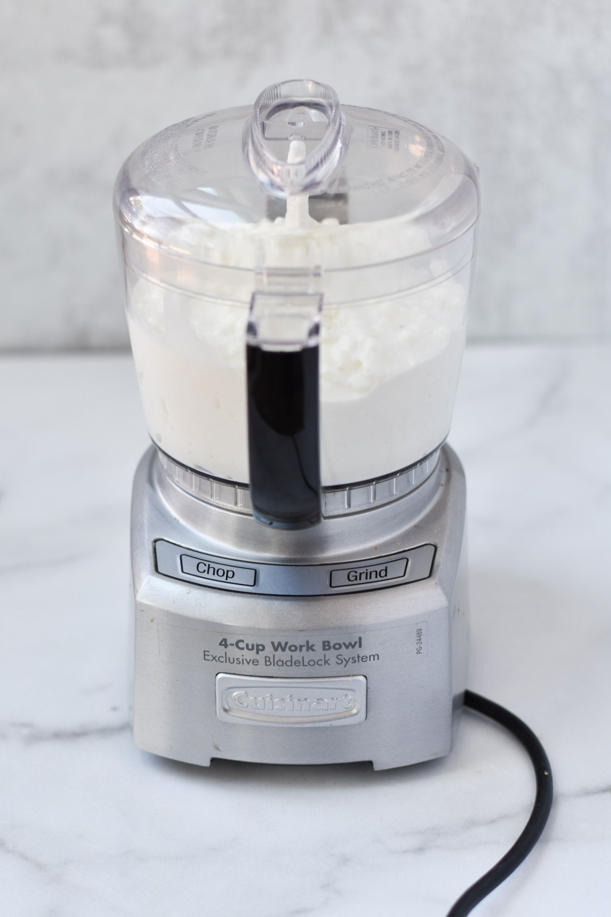 A mini food processor filled with cottage cheese on a table.
