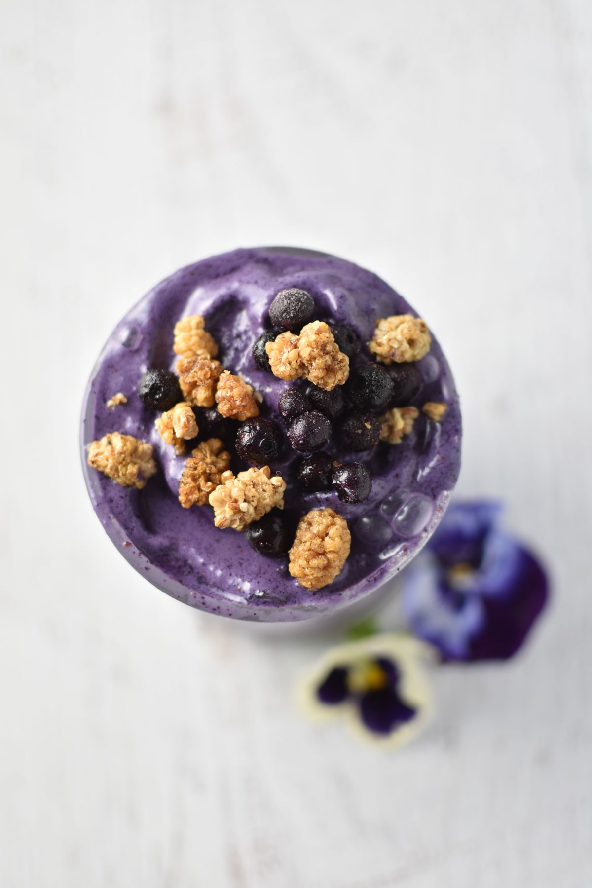 Dried mulberries and blueberries sprinkled on top of a blueberry smoothie.