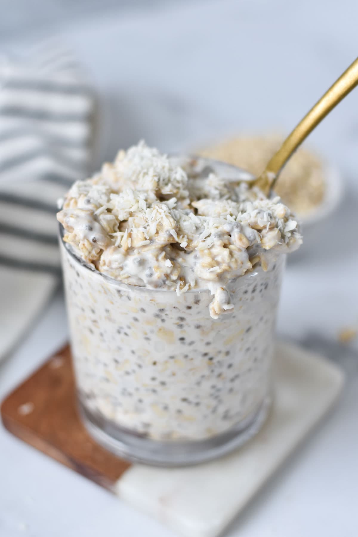 A cup of coconut overnight oats with shredded coconut on top. 