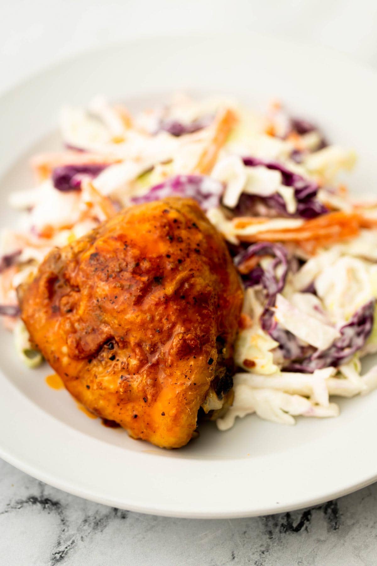 Buffalo chicken on a plate with apple coleslaw.