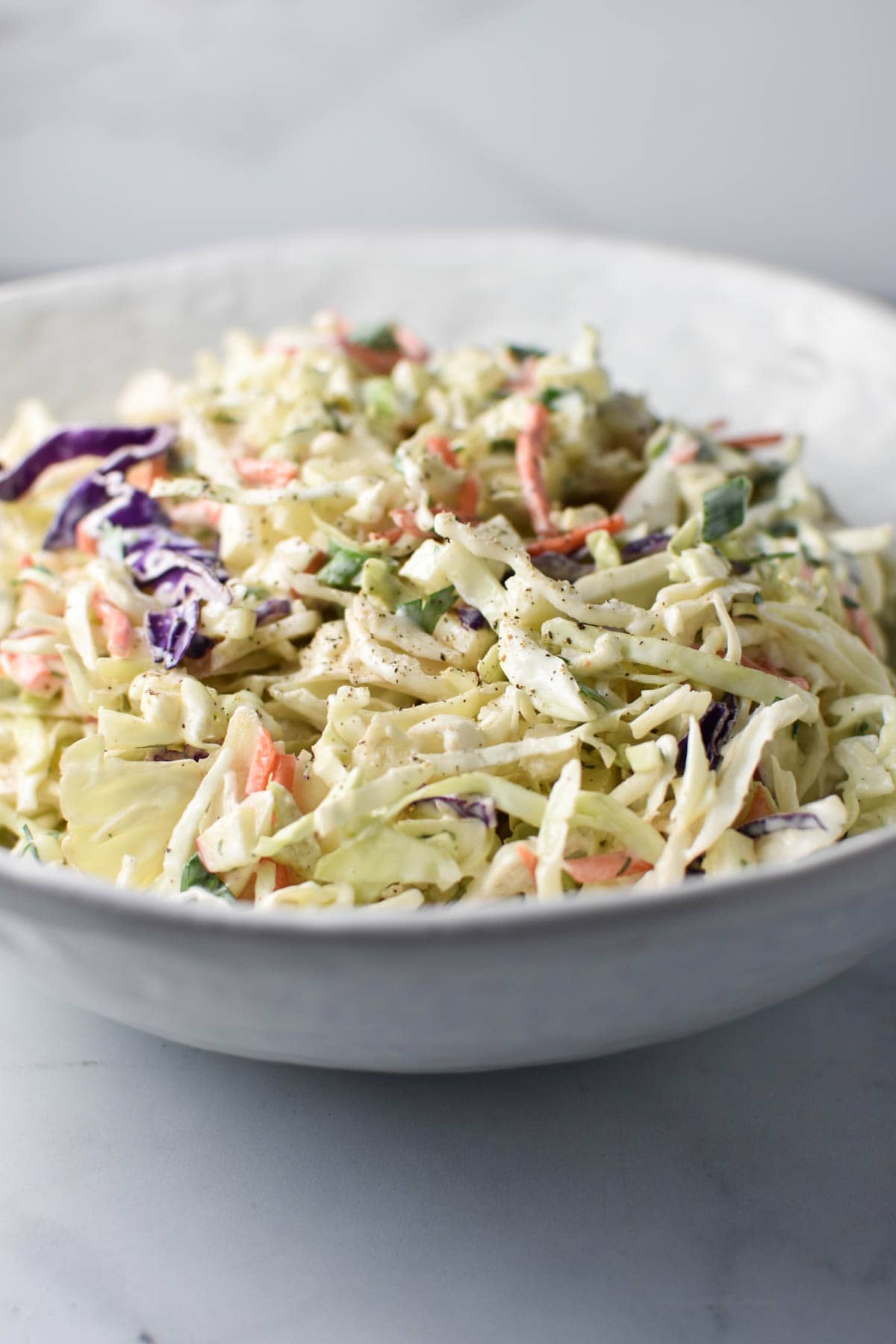 A creamy coleslaw mixed in a white bowl.