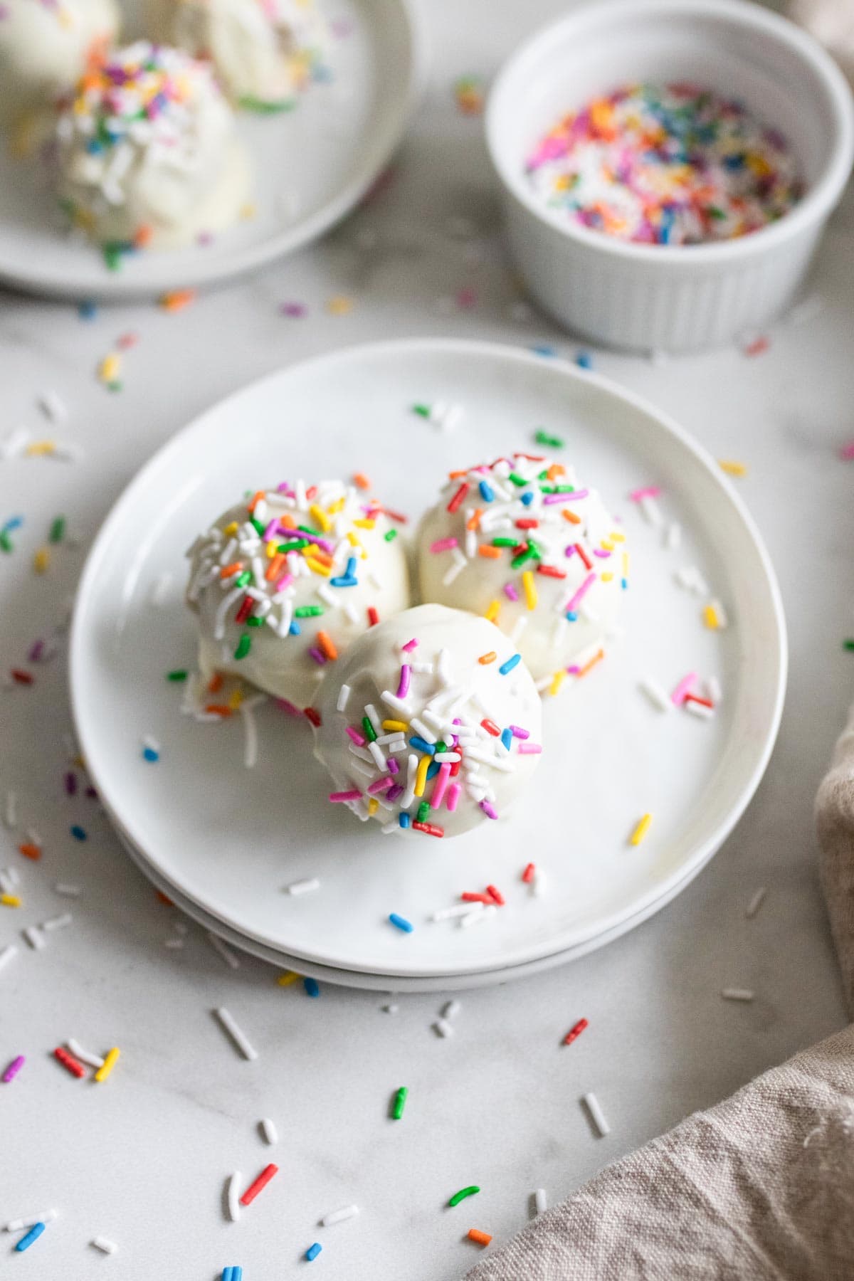 Cake balls on a plate with sprinkles. 