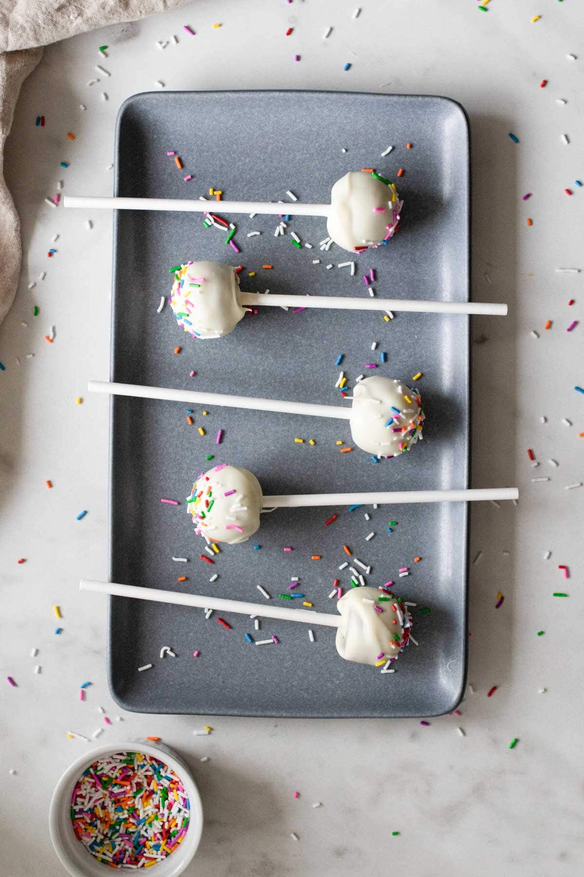 Cake pops letting the white chocolate cool and harden on a sheet pan.