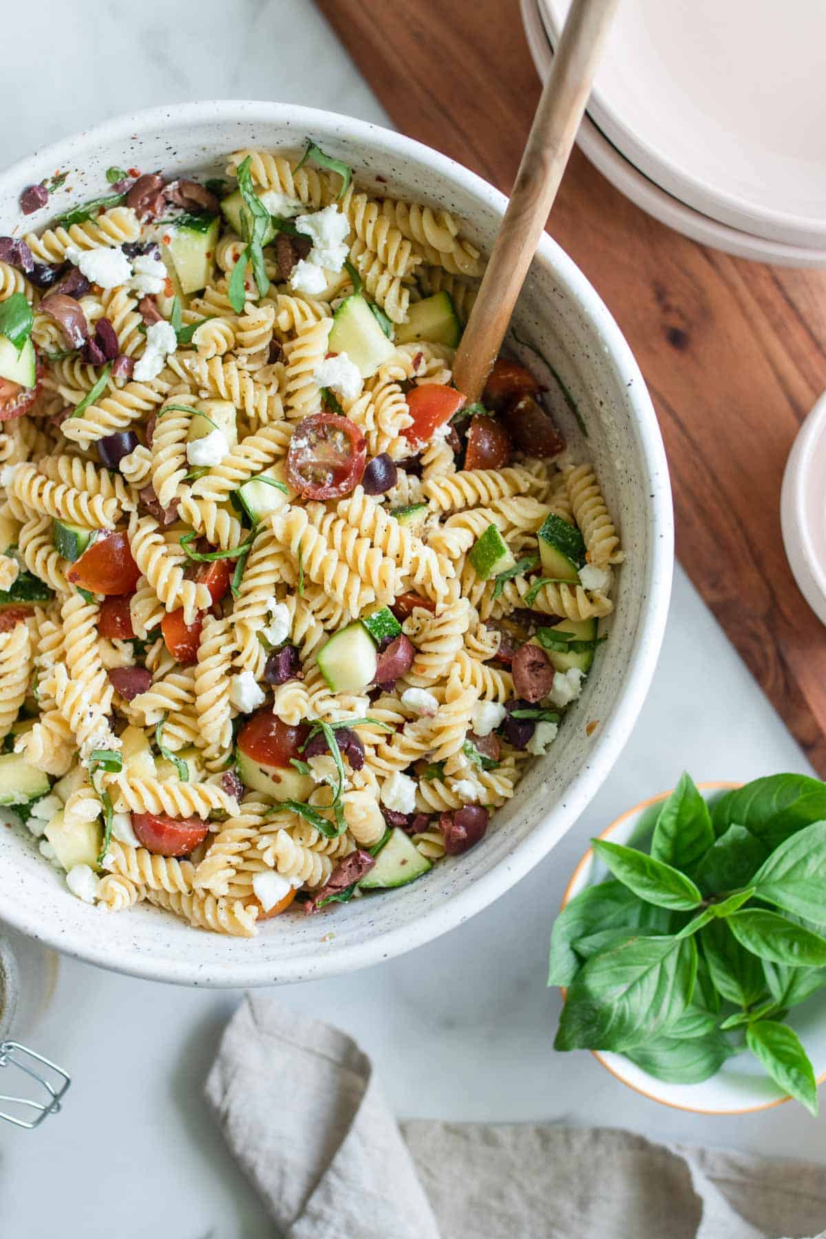 Mixing together pasta salad with a wood spoon.