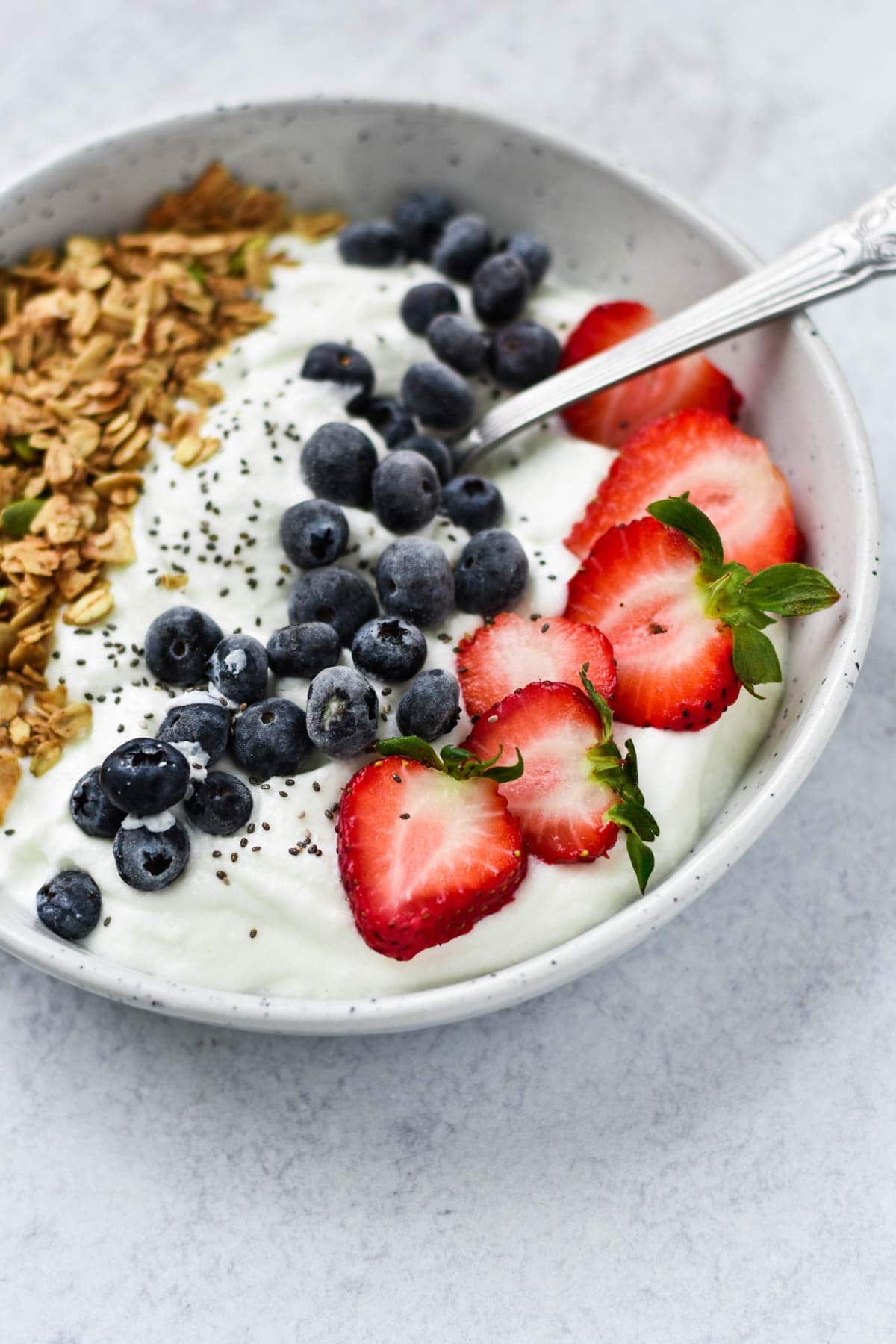 Cottage cheese topped with mixed berries and granola in a white bowl.