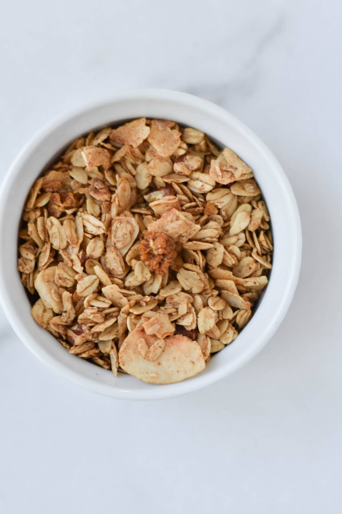 A cup of granola on a marble background.