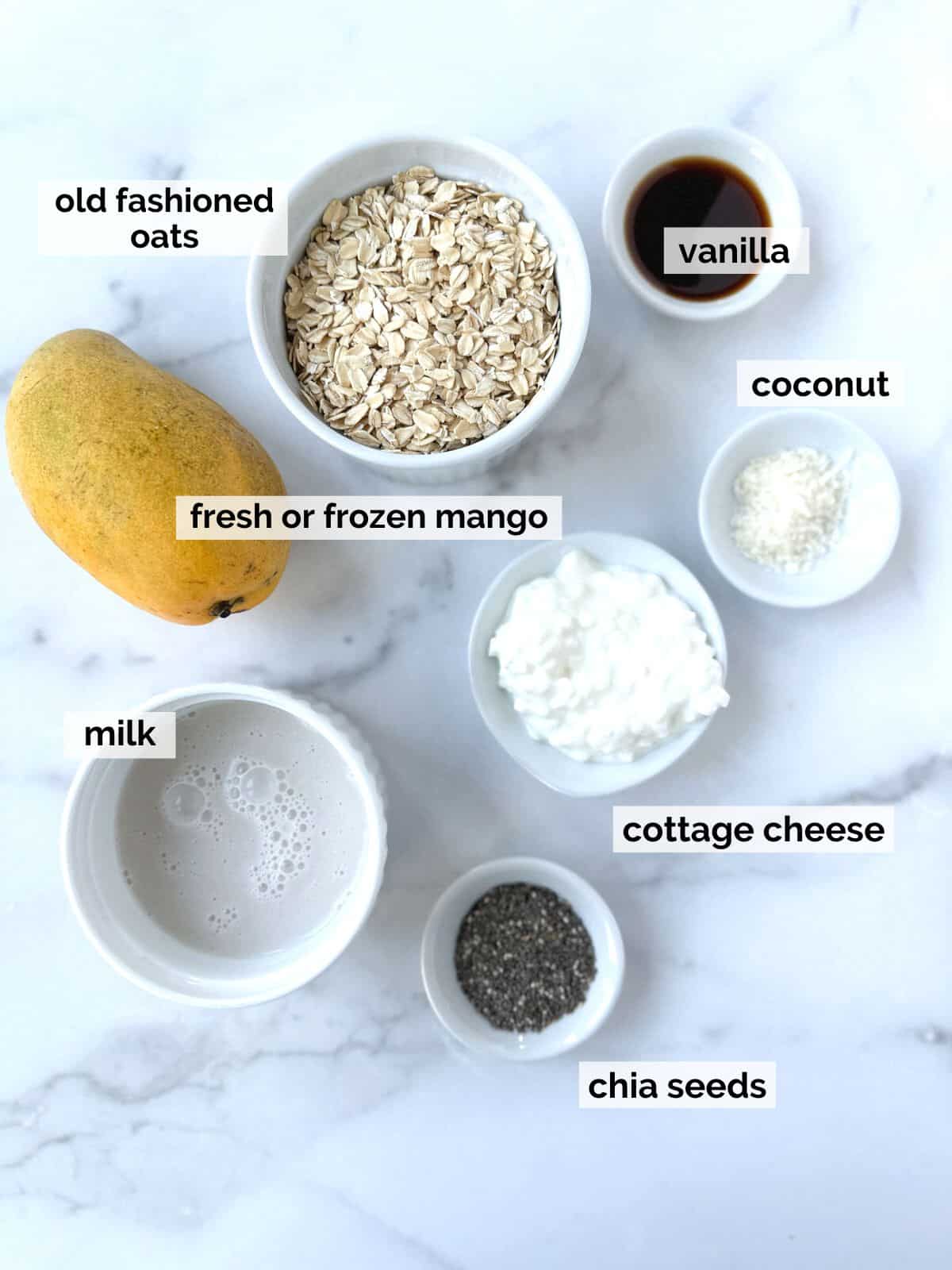 Ingredients for mango overnight oats on a marble background.