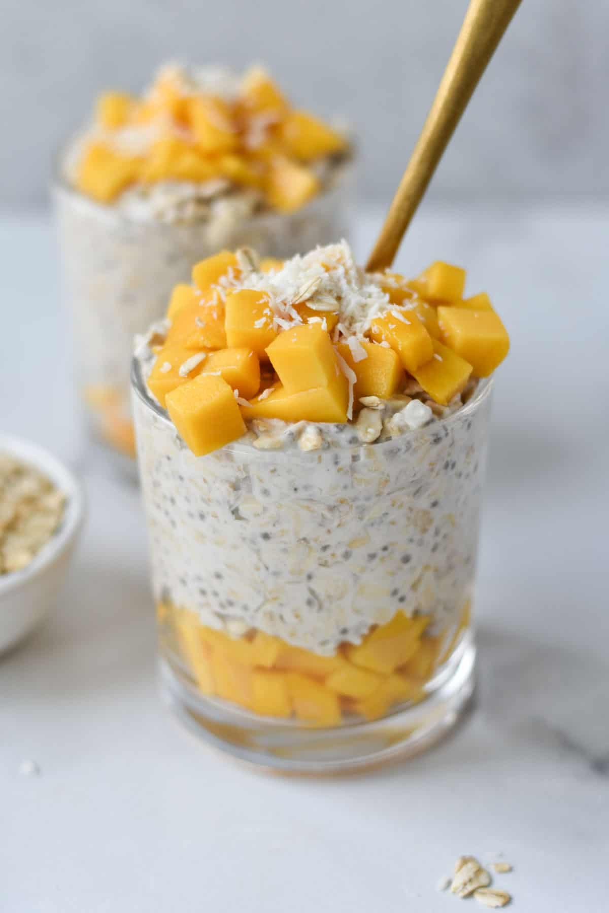 Layers of mango and overnight oats in a jar.
