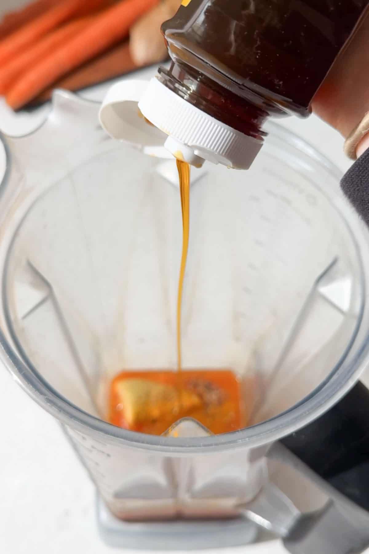 Adding ginger, turmeric and honey to a blender with carrot juice.