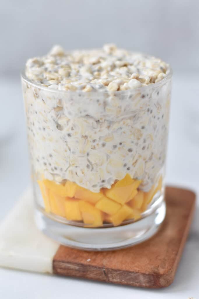 Filling overnight oats on top of mango slices.