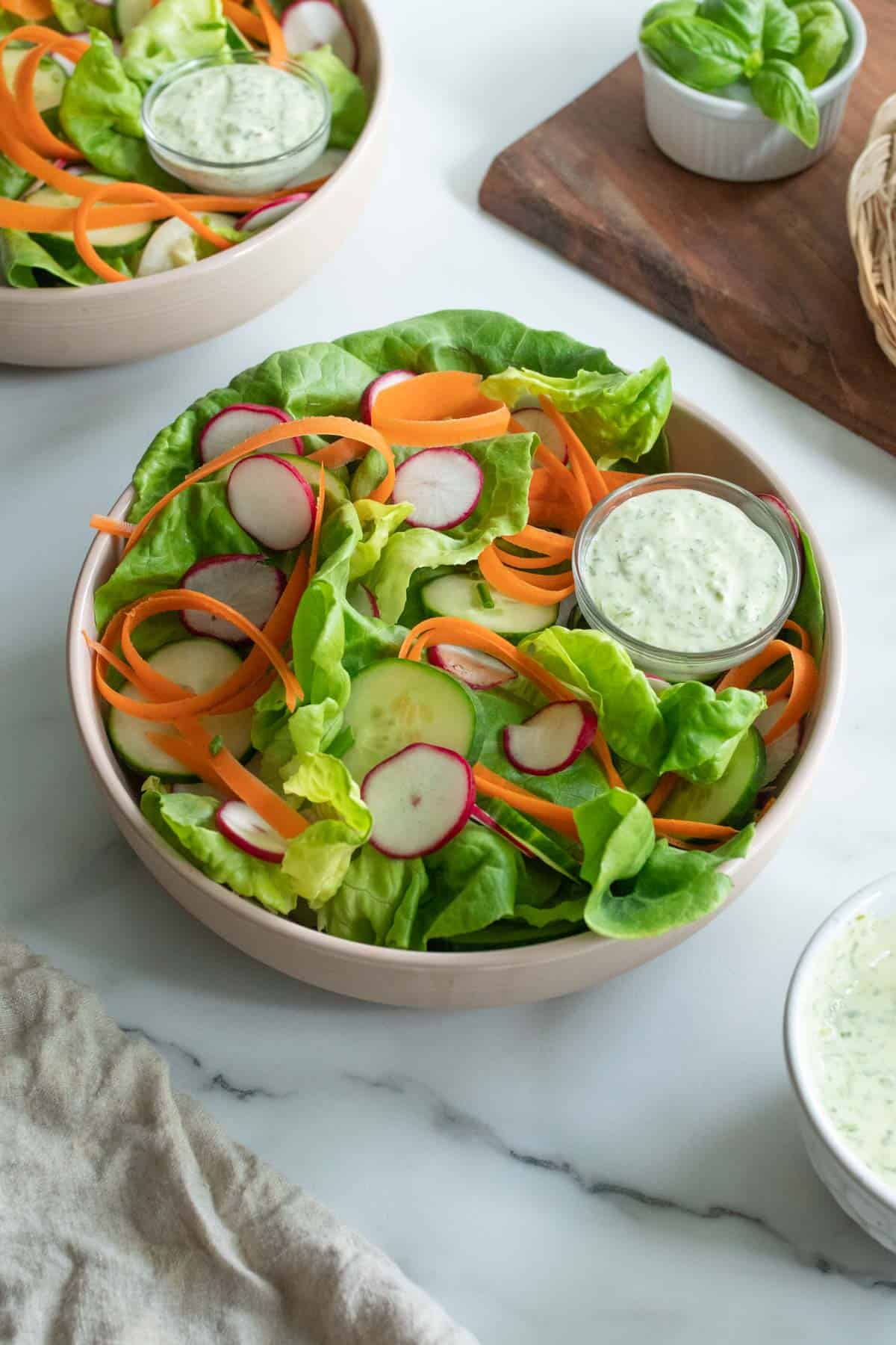 A bibb lettuce salad in a bowl with a creamy dressing on the side.