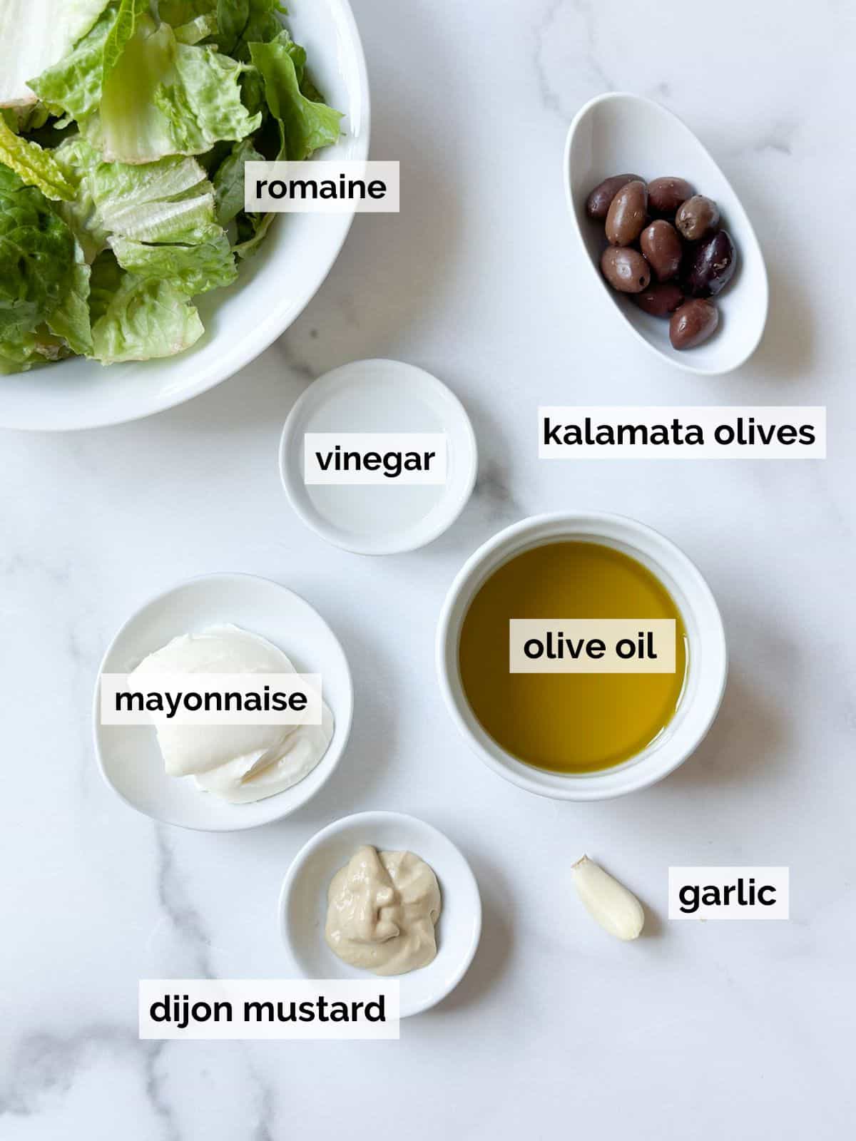 Ingredients for Caesar dressing on a white marble table.