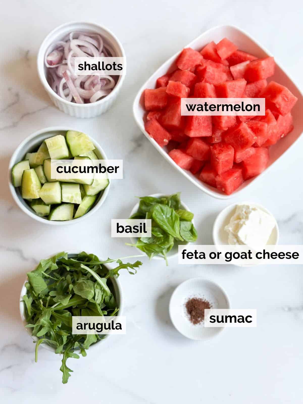 Ingredients for watermelon basil salad on a marble table.