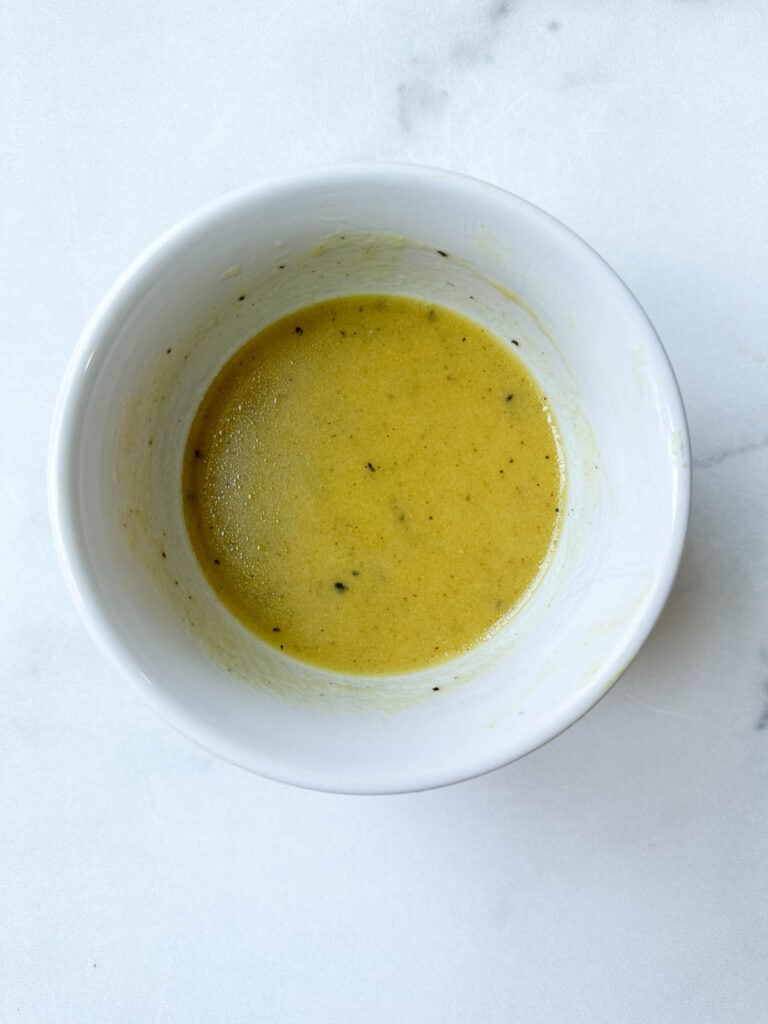 Vinaigrette in a white bowl whisked together.