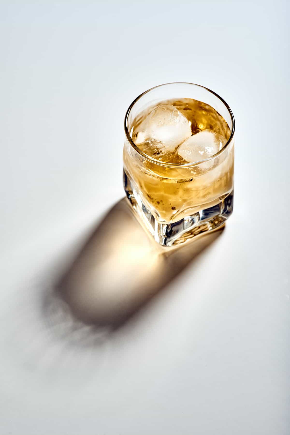 A glass of liquor on the rocks on a white background.