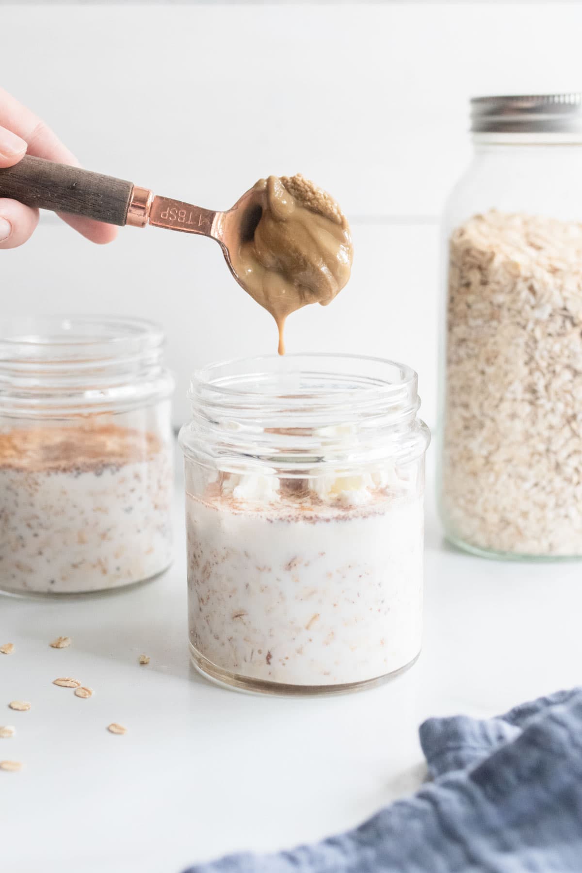 Pouring sunflower seed butter on top of a jar of overnight oats.