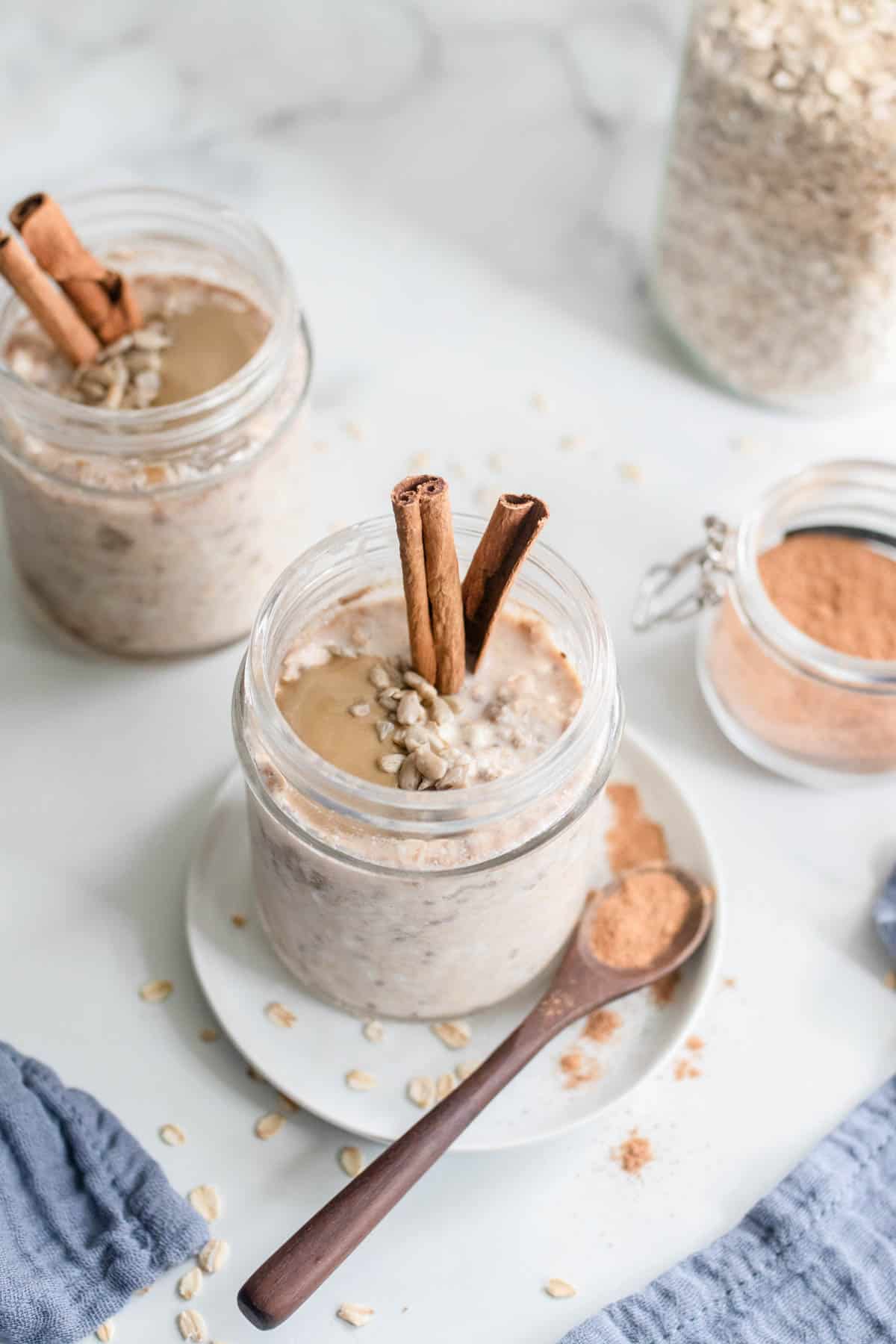 Two jars of overnight oats with cinnamon sticks.