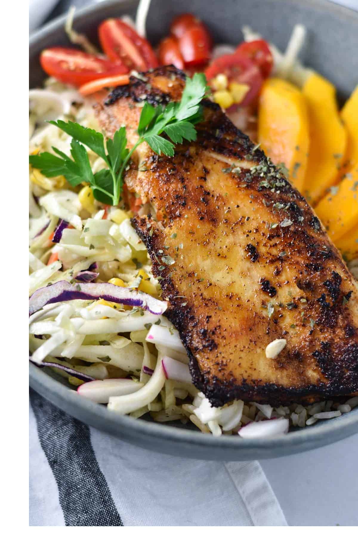 Seared Cobia fillet next to slaw and sliced mangoes.