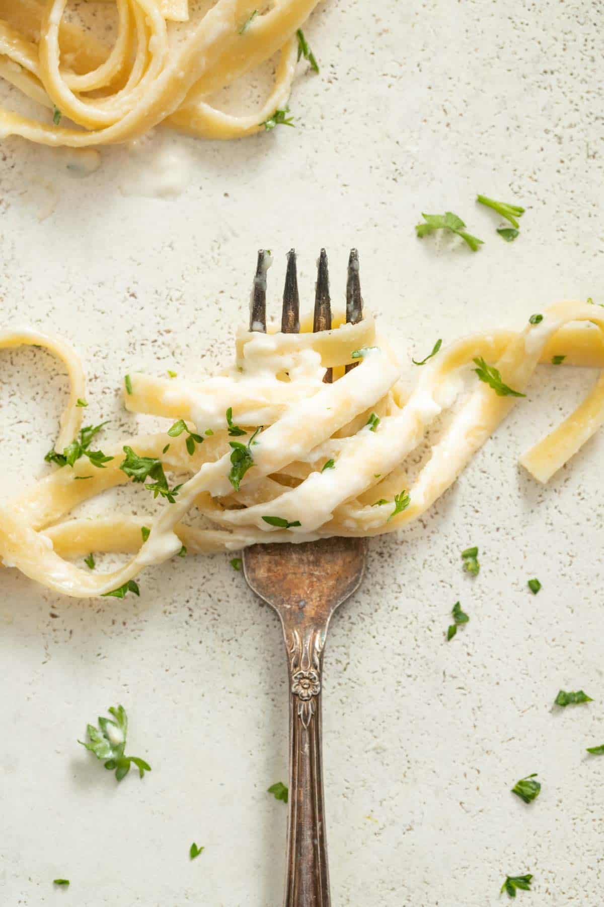 Creamy pasta wrapped around fork tines.