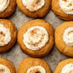 A baking sheet with pumpkin cookies topped with cream cheese frosting and cinnamon.