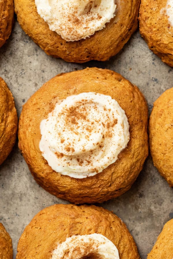 A baking sheet with pumpkin cookies topped with cream cheese frosting and cinnamon.