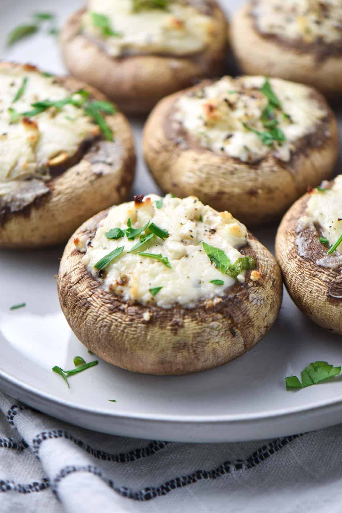A Boursin stuffed mushroom on a plate with cheese melting off the sides.
