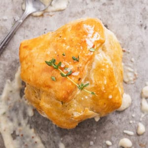 A golden brown chicken puff pastry pocket topped with a sprig of thyme and a dijon cream sauce.