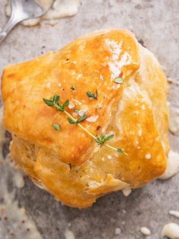 A golden brown chicken puff pastry pocket topped with a sprig of thyme and a dijon cream sauce.