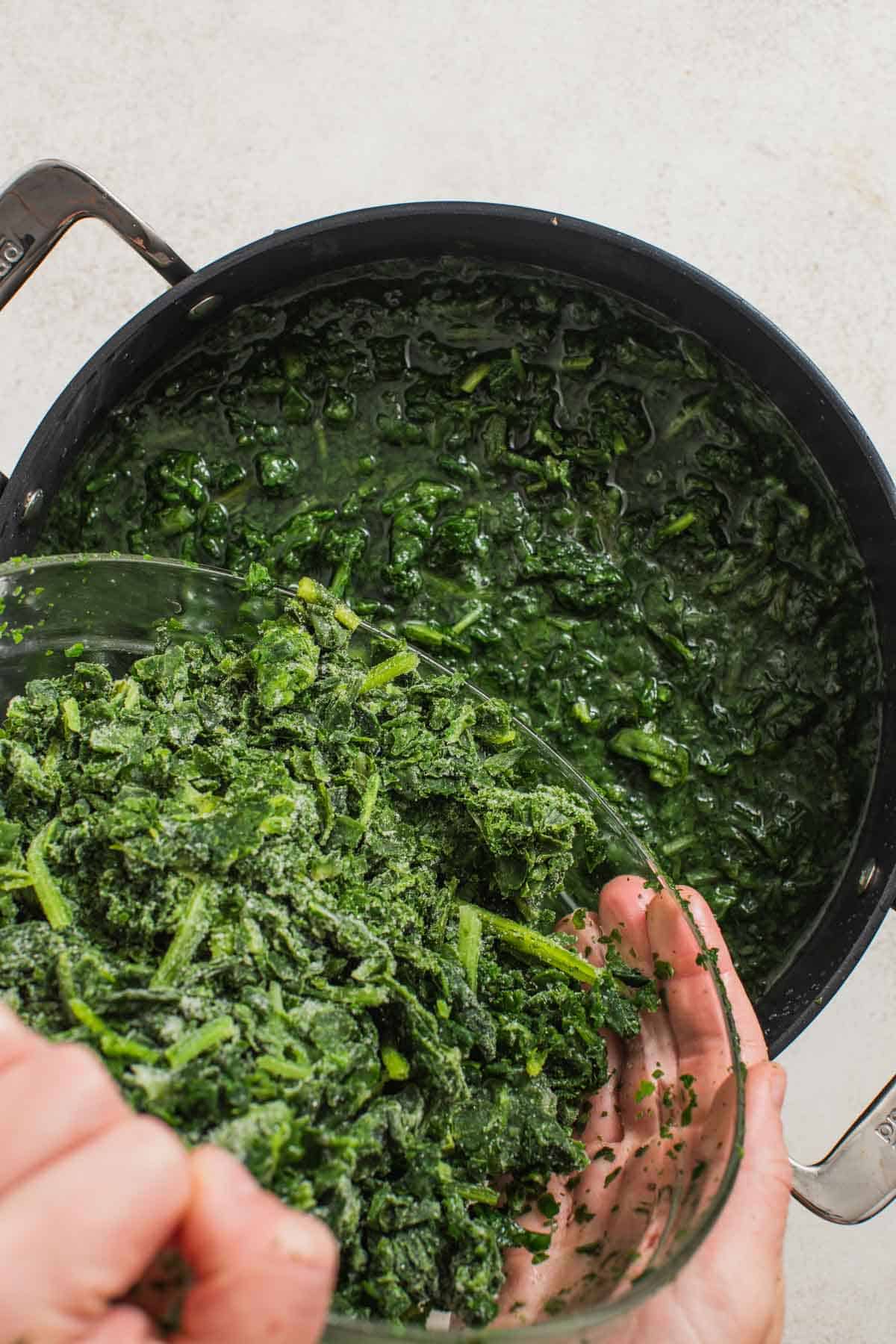 Pouring frozen spinach into a pot of hot water.