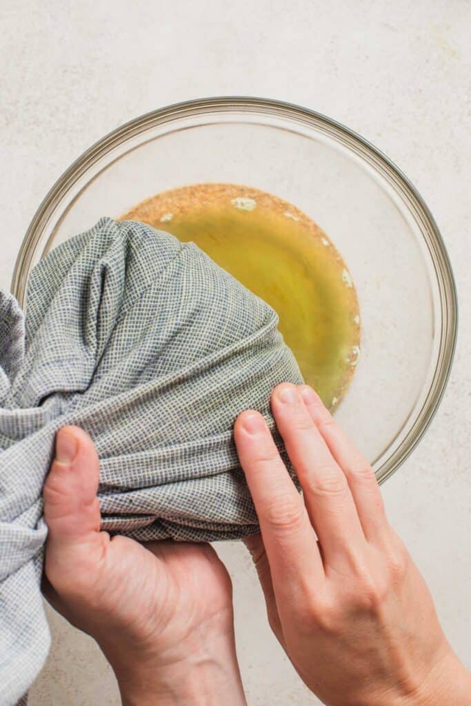 Squeezing liquid from cooked frozen spinach out into a bowl. 