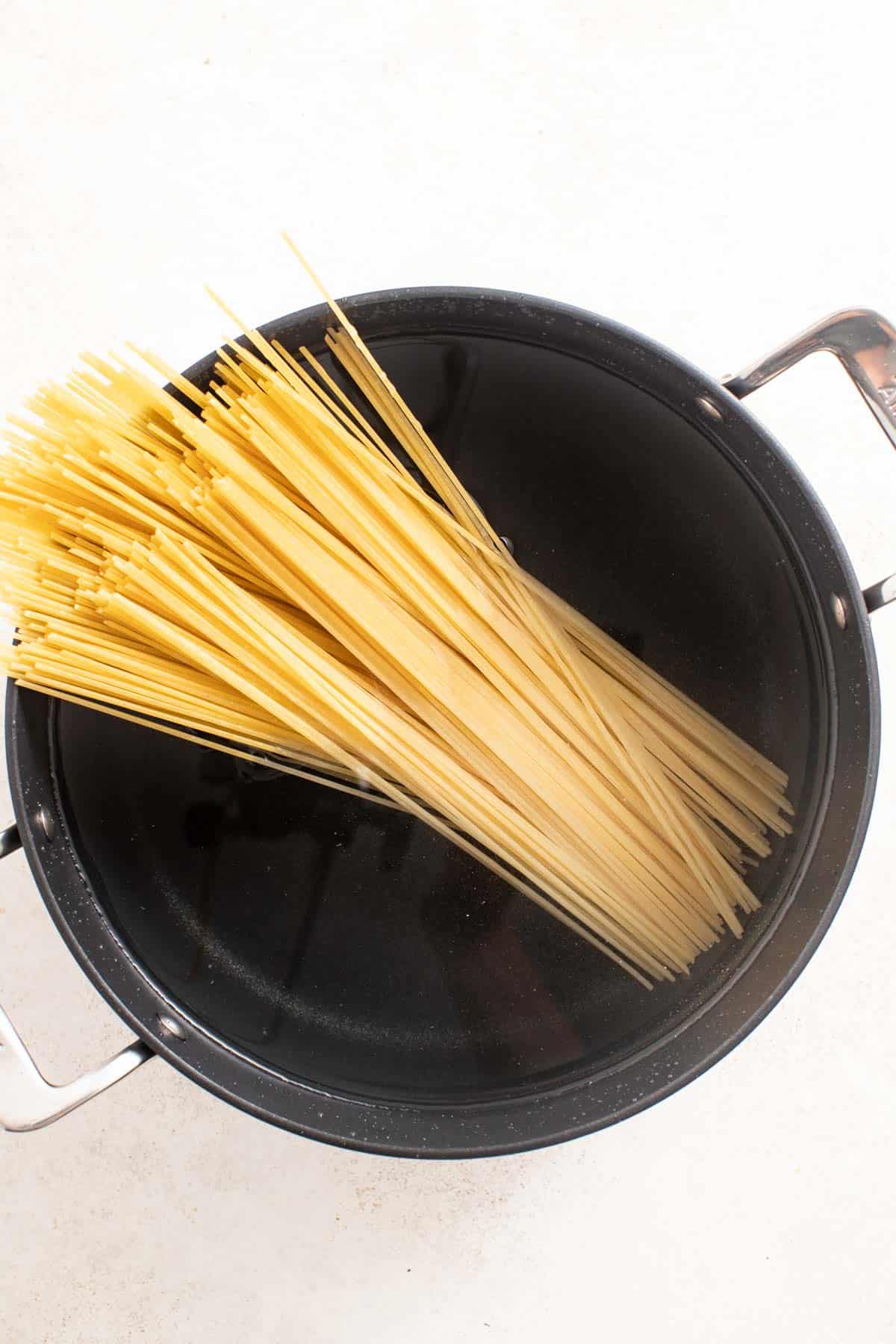 Linguine in a black pot of water.