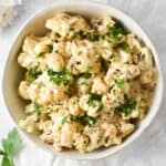Cauliflower covered in a cheese sauce and topped with parsley.