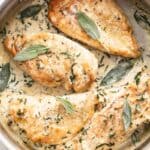 Four chicken breasts topped with sage in a creamy sauce.
