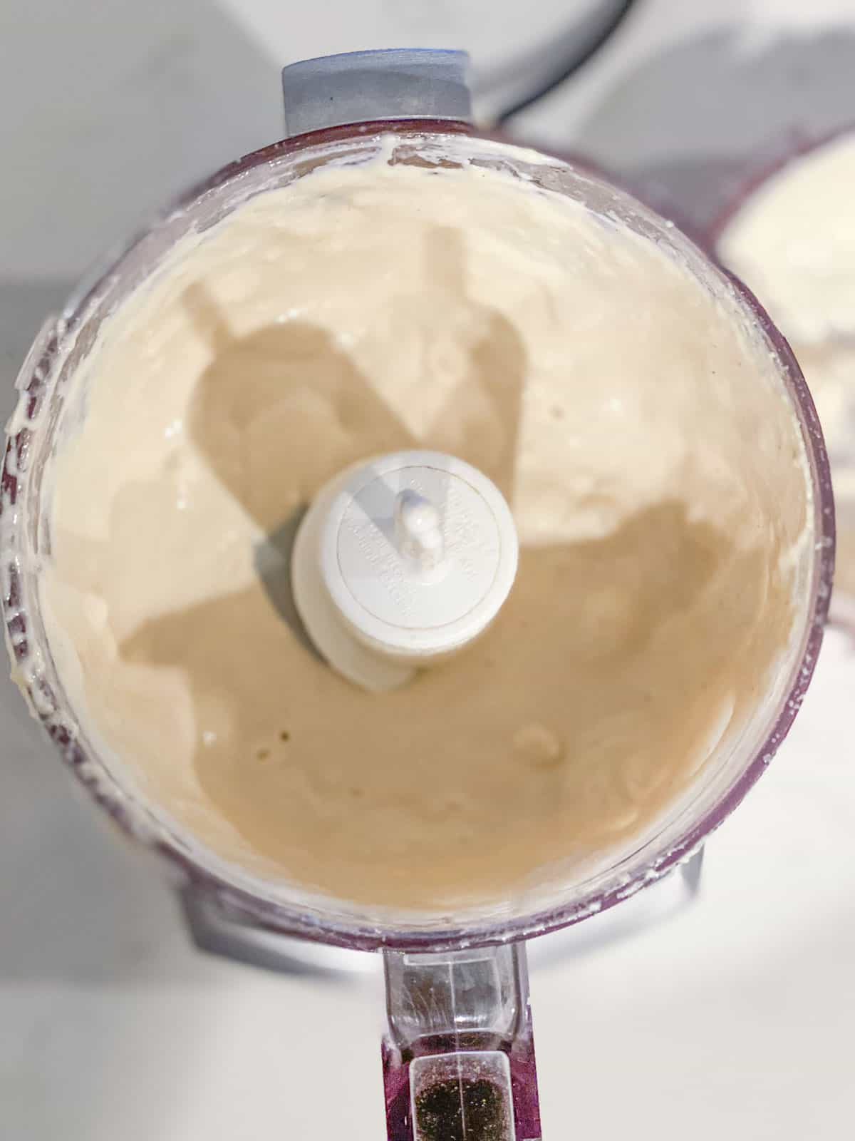 A small food processor with a tahini dressing inside.