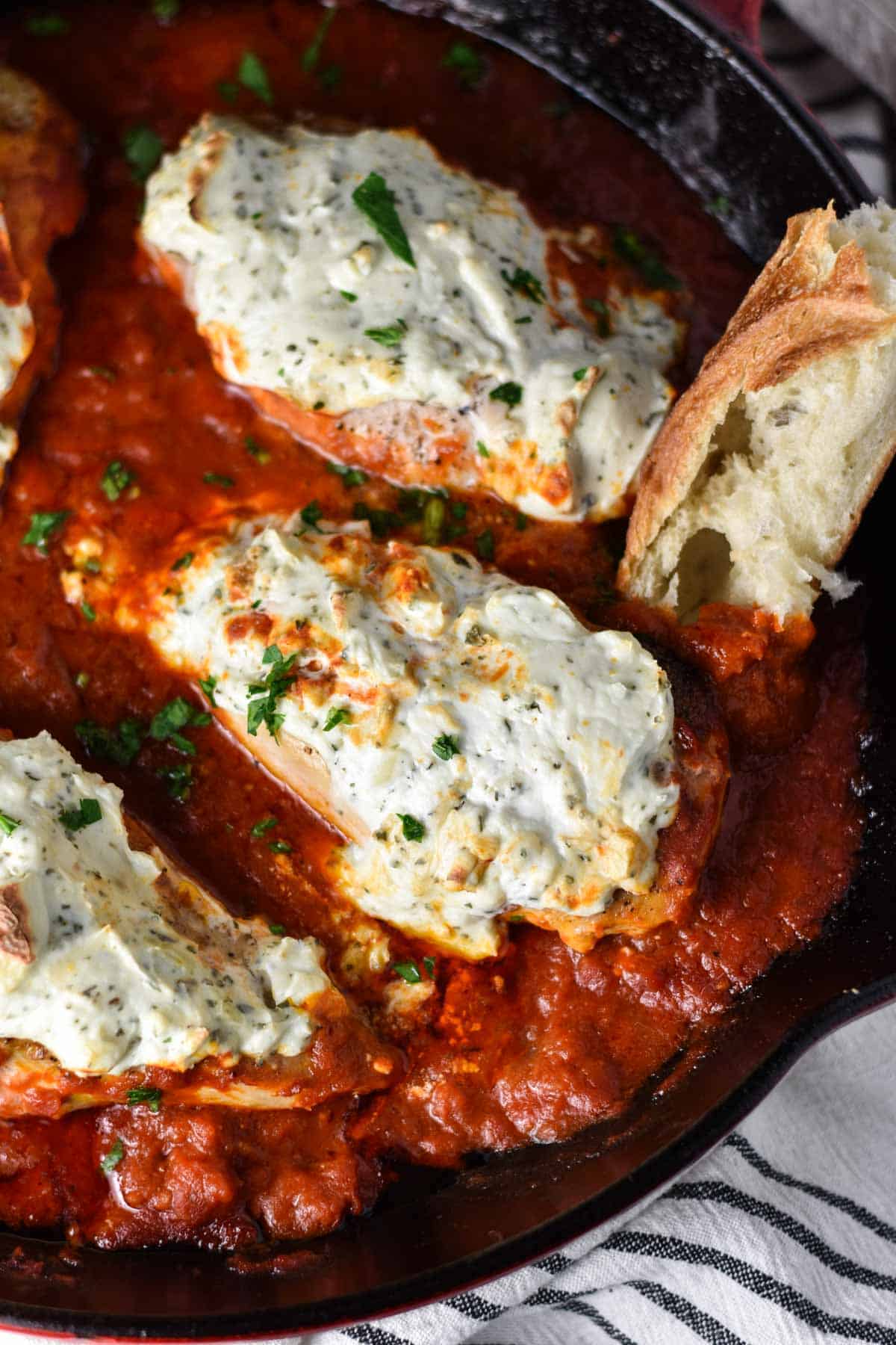 Bread dipping into a chicken with marinara sauce and ricotta cheese.