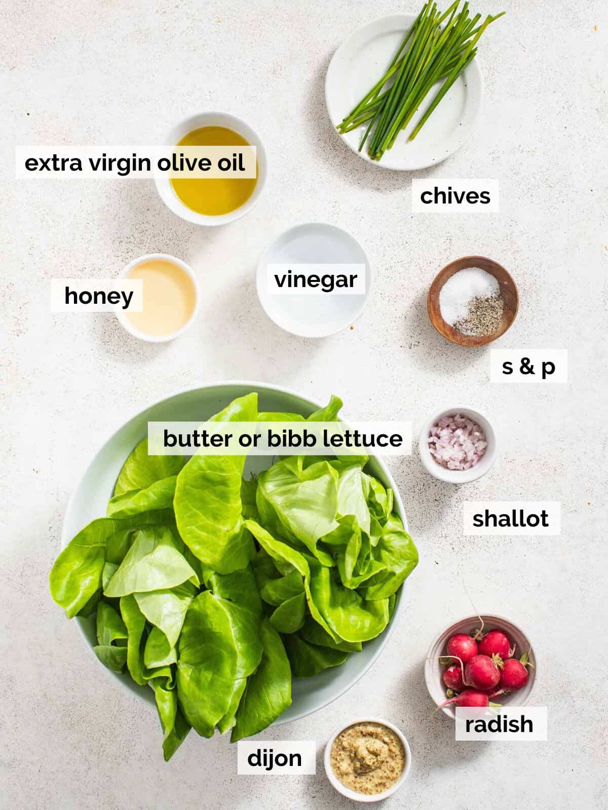 Ingredients for a butter lettuce salad on a white table.