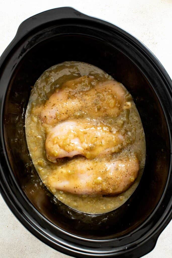 Chicken breasts and salsa in a crockpot uncooked.