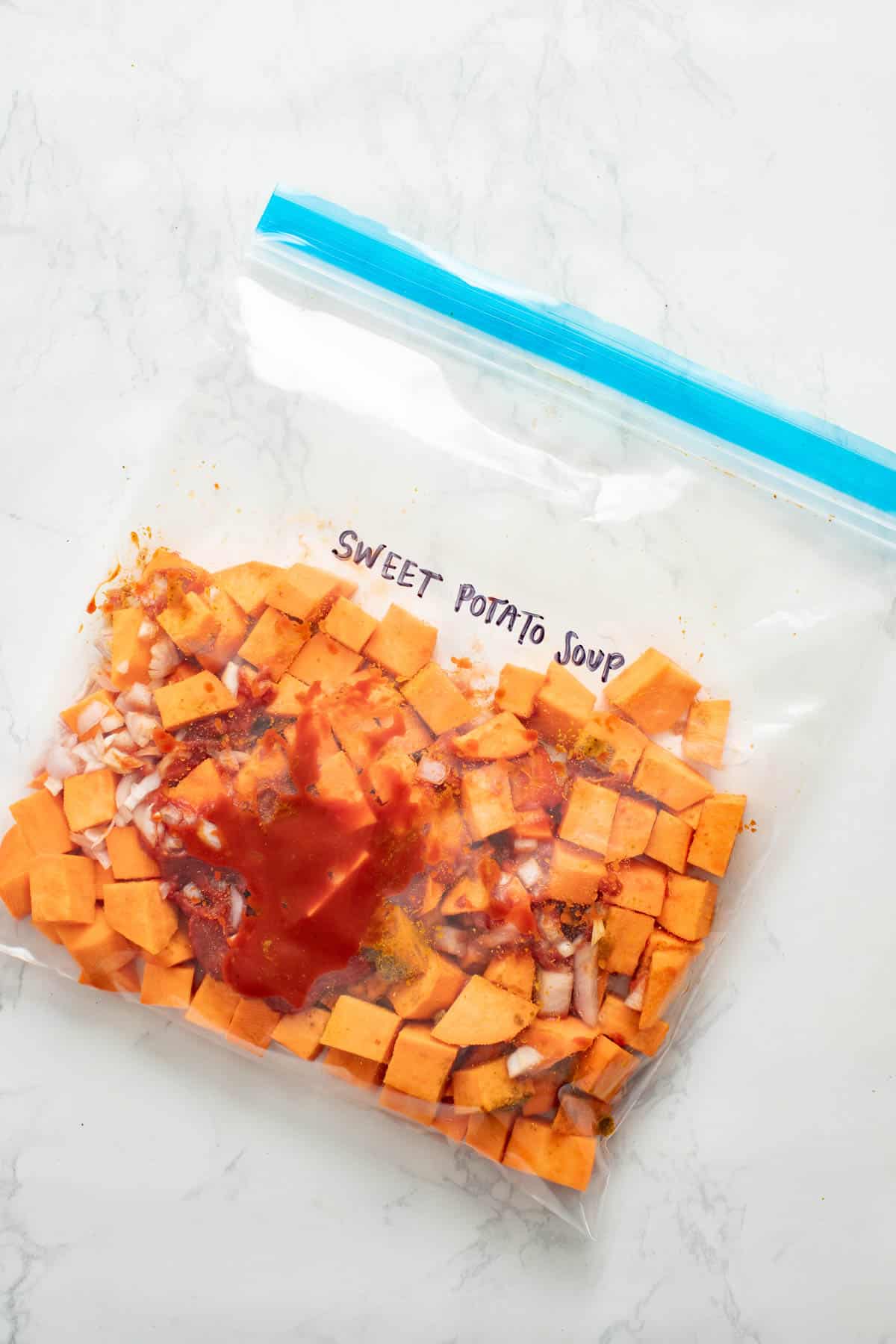 A freezer bag of ingredients with sweet potatoes and spices inside for meal prepping.