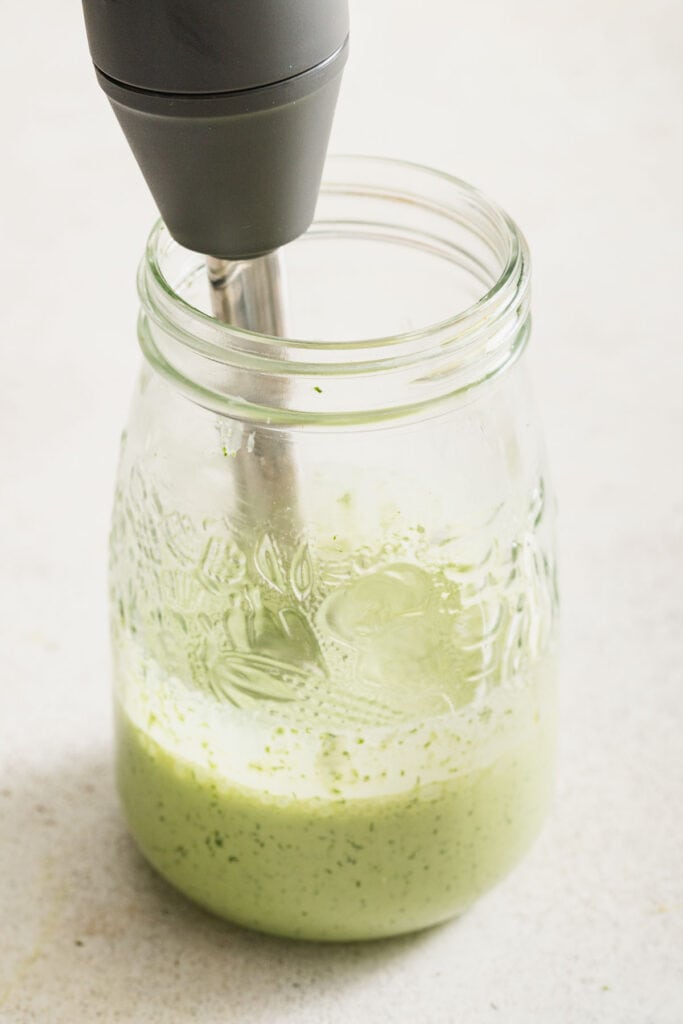 Ingredients for green goddess being blended with an immersion blender.