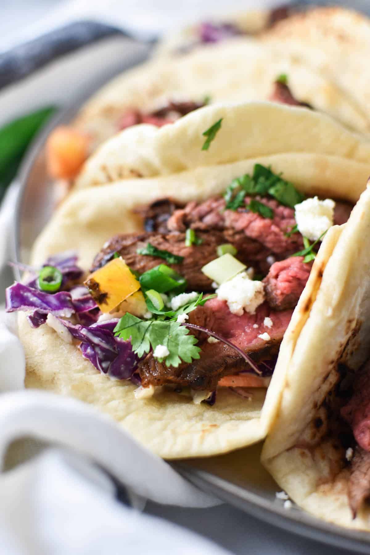 A close up shot of sliced flank steak on a tortilla.