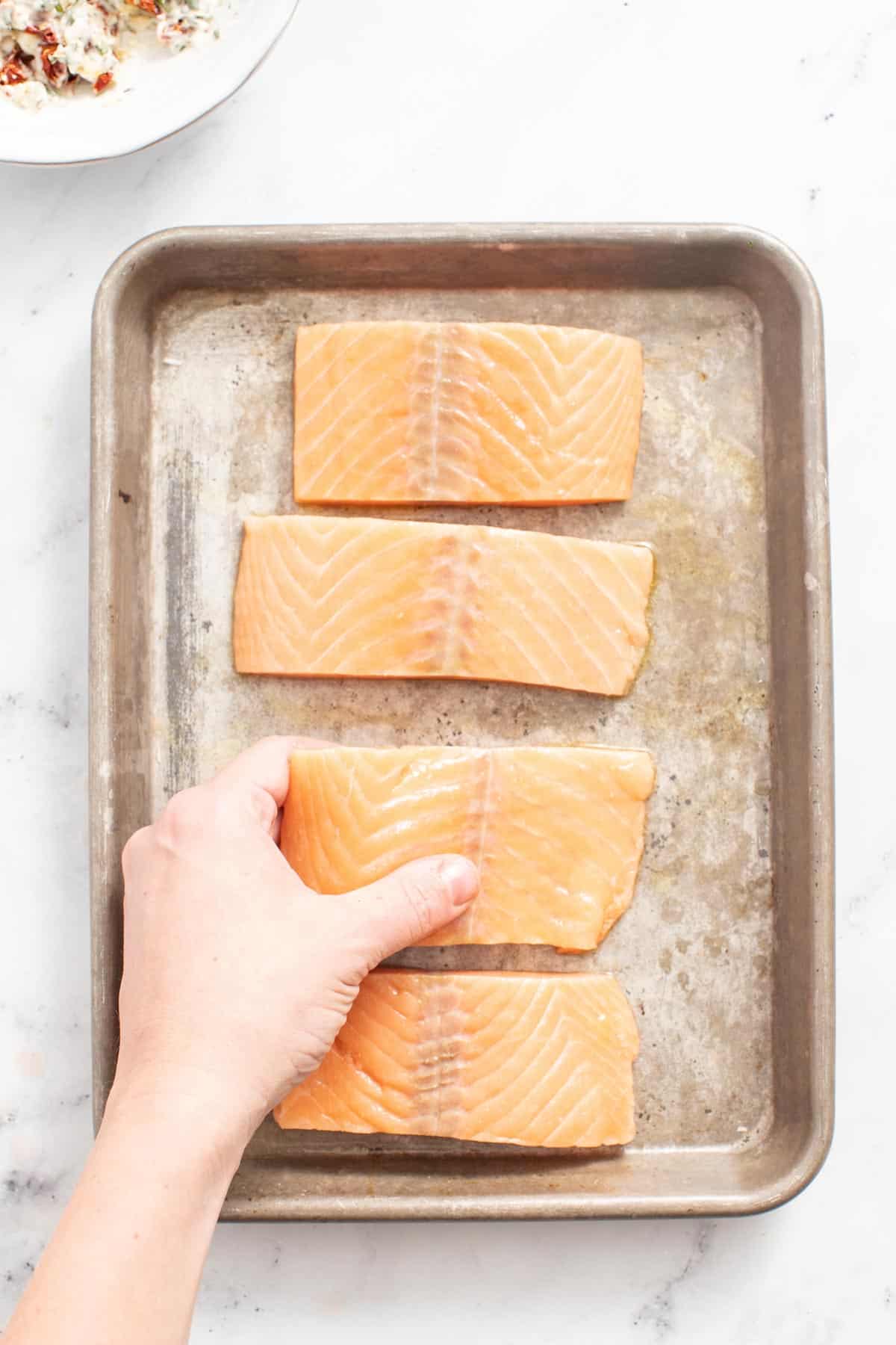 Pieces of raw salmon fillets on a sheet pan. 