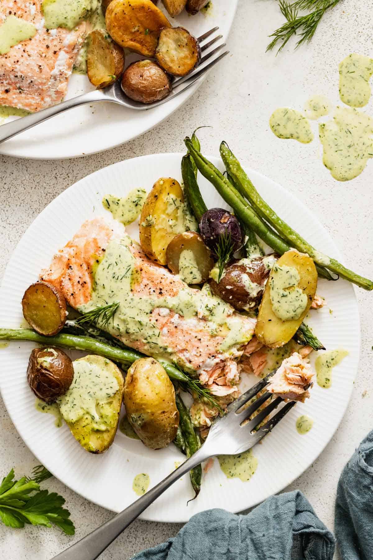 Salmon and green beans on a white plate with a fork.