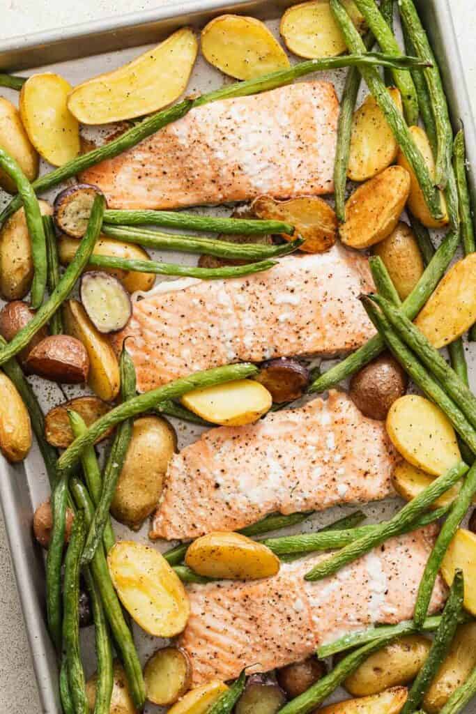 Salmon, green beans, and potatoes on a sheet pan after baking.