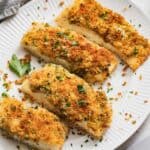 Panko and parsley crusted halibut fillets on a white plate.