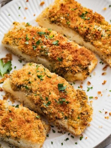 Panko and parsley crusted halibut fillets on a white plate.