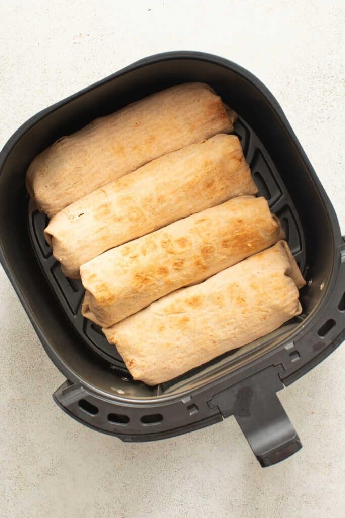 Chicken wraps lined up in an air fryer after frying.