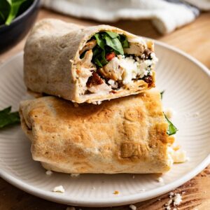 Chicken wraps stacked on top of each other on a white plate.