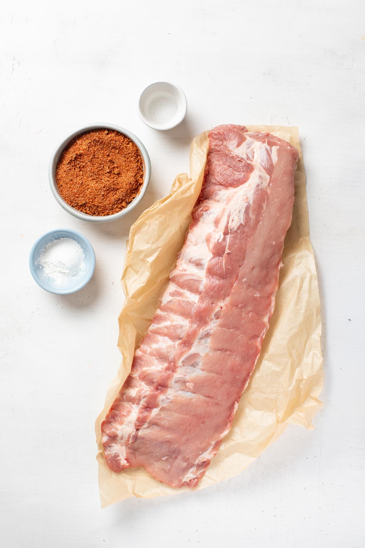 Ingredients for baby back ribs with a dry rub on a white background.