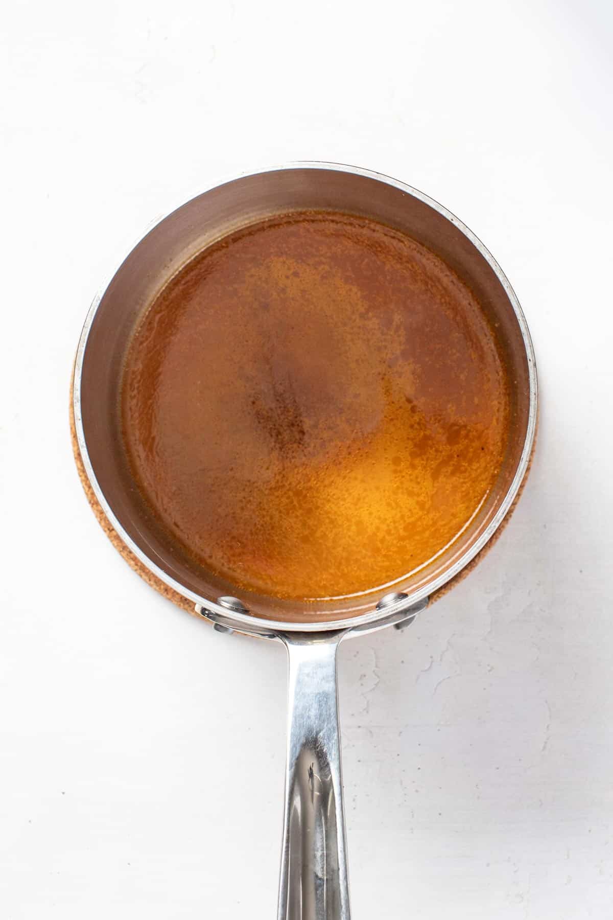 Adding the spices and leftover juices to a small saucepan.